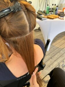 Styling-Szene im Zelt: Kundin sitzt, während am Haar gearbeitet wird