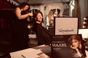 Styling im Zelt: Person arbeitet am Haar, Werbematerial im Vordergrund