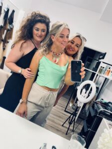 Selfie im Salon: Drei Frauen posieren vor Spiegel und Ringlicht