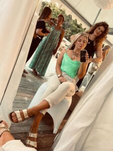 Spiegelaufnahme: Frau sitzt beim Styling, Personen arbeiten im Hintergrund