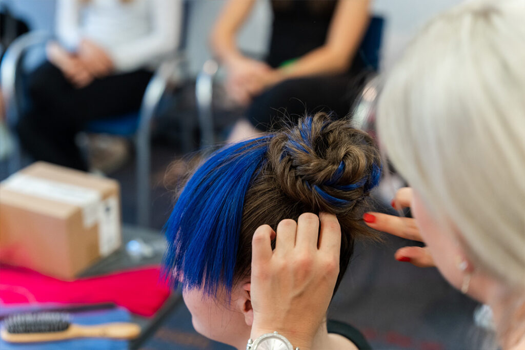 Nahaufnahme von geflochtenen Haarsträhnen in der Farbe Deep Saphire während des Stylings im Backstage-Bereich.