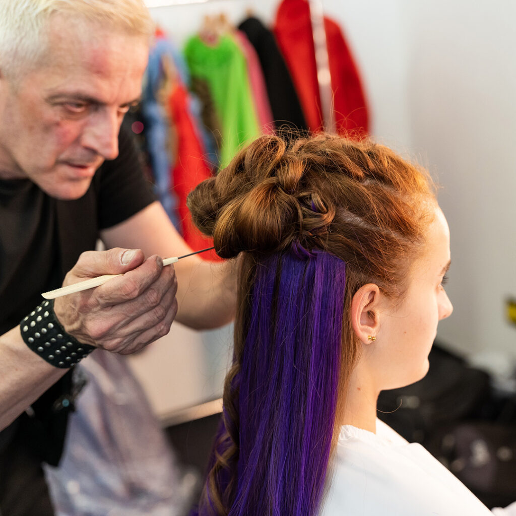 Diego arbeitet leuchtendes Violett in die Haare der Tänzerin ein