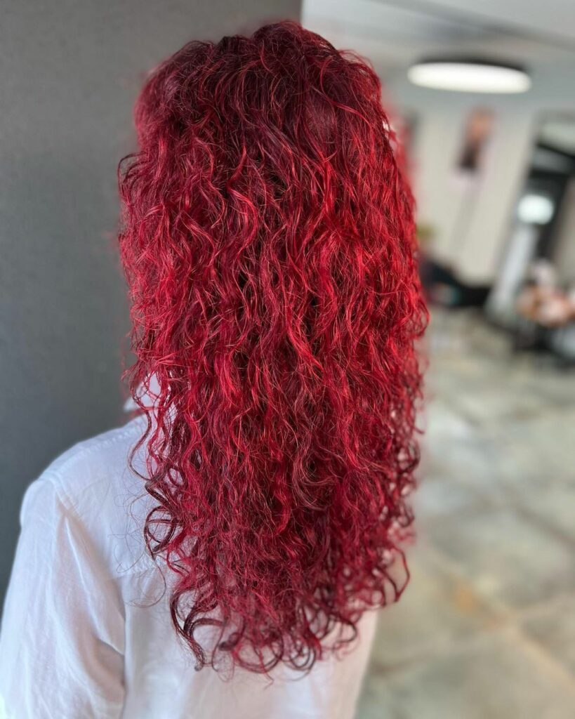 Seitenansicht von lockigem, tiefrot gefärbtem Haar mit feiner Struktur und natürlichem Volumen.