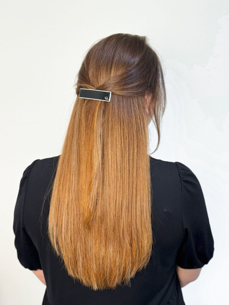 Glattes, halboffen getragenes Haar mit schlichter Great-Lengths-Spange, ideal für einen eleganten Alltagslook.
