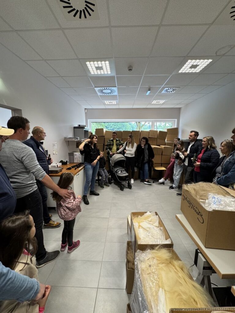 Familien und Mitarbeitende in einem Raum mit Kartons und Produktionsmaterial