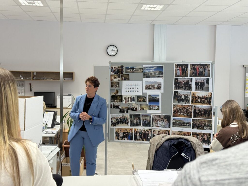 Vortragssituation im Raum, im Hintergrund eine Fotowand mit Teamfotos